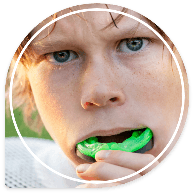 Young boy placing green athletic mouthguard into his mouth
