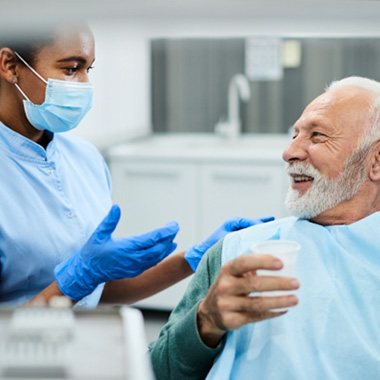 Smiling patient talking to dentist while sitting in treatment chair