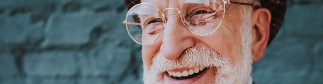 Man smiling with blue-brick wall in the background
