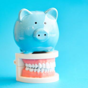 Blue piggy bank sitting on top of a dental model