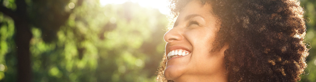 profile view of woman outside smiling with sun shining on her face