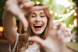 Young woman framing her smile with hands. 