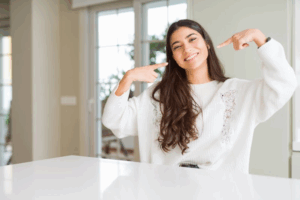 Woman pointing to her bright smile while sitting at a table